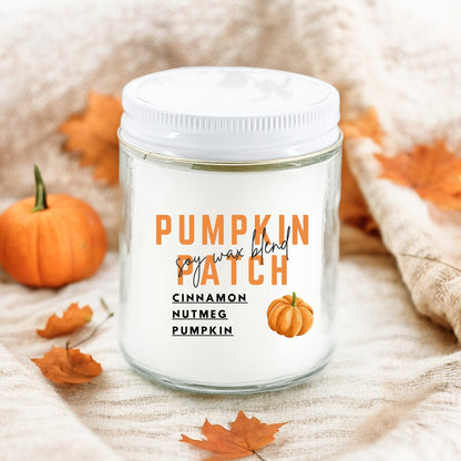 A white jar candle with a label that reads 'Pumpkin Patch' and has images of pumpkins and autumn leaves. The candle is displayed with a small pumpkin and leaves in the background.